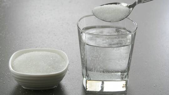 在玻璃杯里把糖和水混合