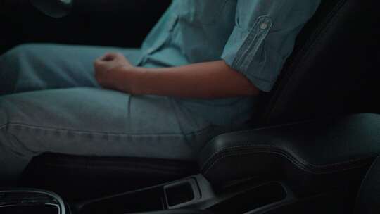 一个女人坐在驾驶座上的车里。她系好安全带