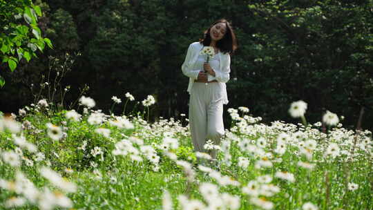 美女手握鲜花漫步草地沐浴阳光慢镜头特写