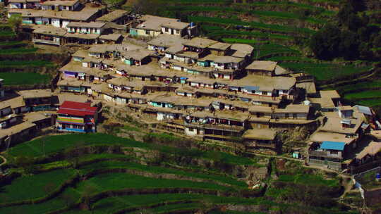 一个村庄在山上的拐角处，人们在散步，屋顶的房子，鸟瞰