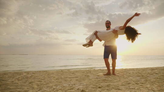 丈夫抱着妻子在沙滩上旋转