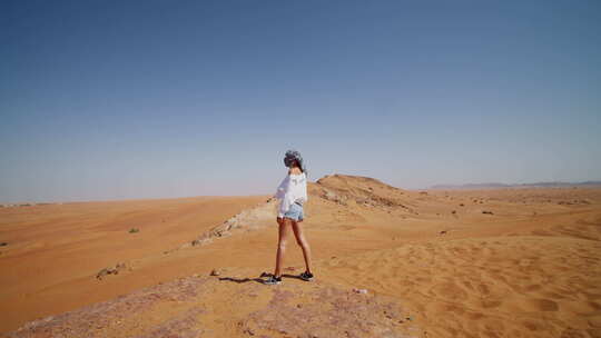 白衣女子站在沙丘边眺望沙漠
