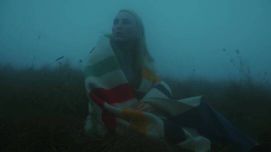 女人坐在雾天的田野上