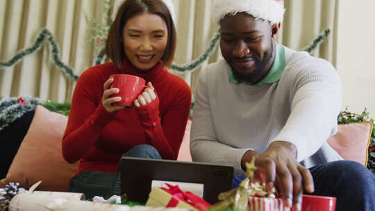 戴着圣诞帽的快乐多样化夫妇在家打圣诞笔记本电脑视频电话的视频
