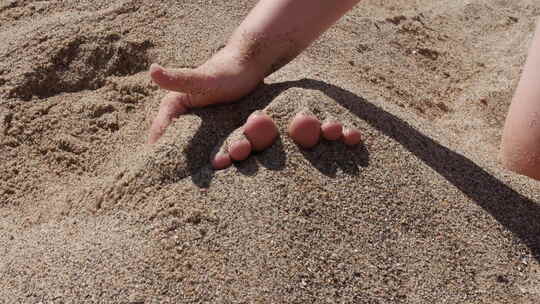 孩子把脚埋在沙子里