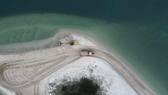 一辆自卸卡车沿着海岸岬角运送沙子，用于侵蚀补给项目。