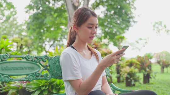 亚洲女性喜欢运动后在公园用手机交流。