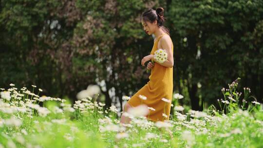 美女拿着一束鲜花走在春天草地上