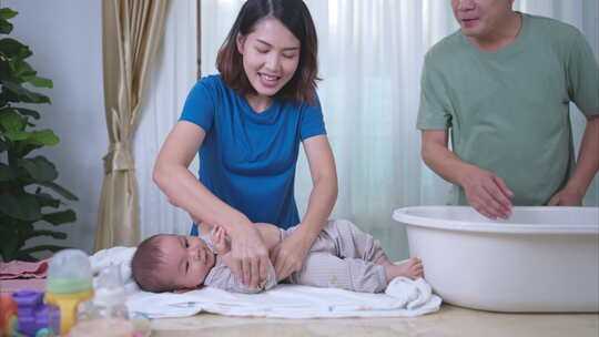 一个小孩子高兴地躺在毛巾上，等待父母涂抹