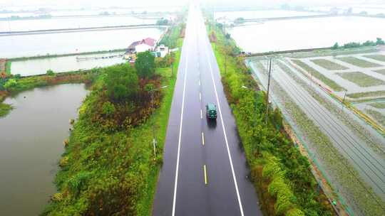 雨中的乡村公路及两侧的池塘农田