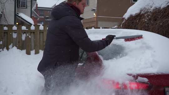 一个男人刷掉车顶上的雪