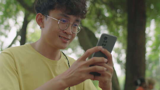 亚洲Zoomer在公园使用智能手机