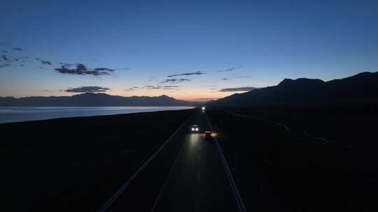 黄昏时分航拍汽车行驶在赛里木湖环湖公路上