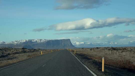 在冰岛广阔的天空和远山的开阔道路上驾驶视