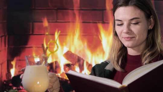 看书时，女人在壁炉前用吸管啜饮饮料