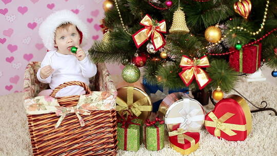 婴儿坐在圣诞树旁的小篮子