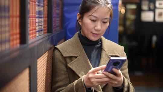 中年女性在书店书架前使用手机