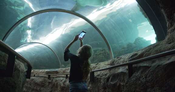 女孩在水族馆给鱼拍照