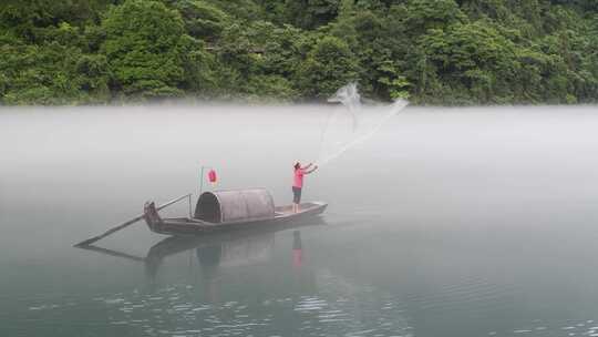 一只小木船正在雾漫东江上撒网捕鱼