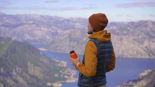 男人在山顶喝水看风景