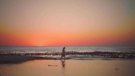 夕阳下女人在海滩上行走