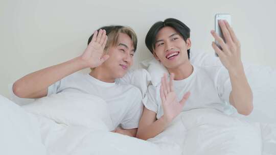 亚洲帅哥同性恋早上在家里与家人在线使用手机视频通话。