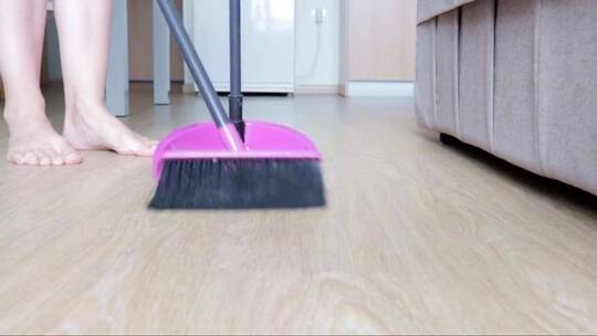 用刷子和扫帚打扫厨房地板的家庭主妇