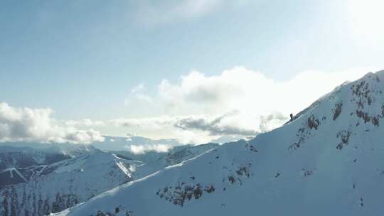 穿着滑雪板沿着雪山脊攀登的人