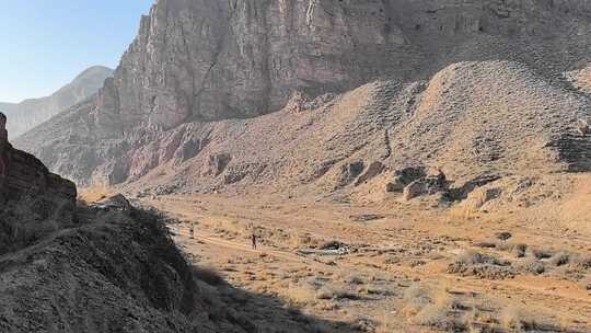 荒凉山地中两人徒步前行的景象