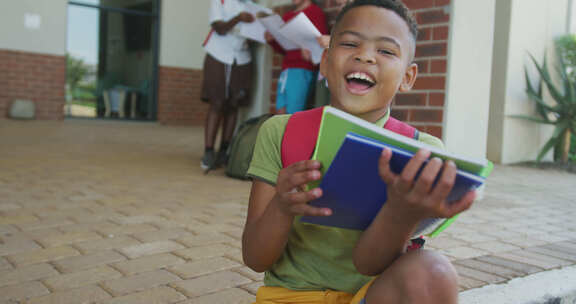 快乐的非裔美国男孩在学校前拿着书的视频