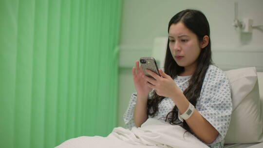 女人坐在病床上使用手机