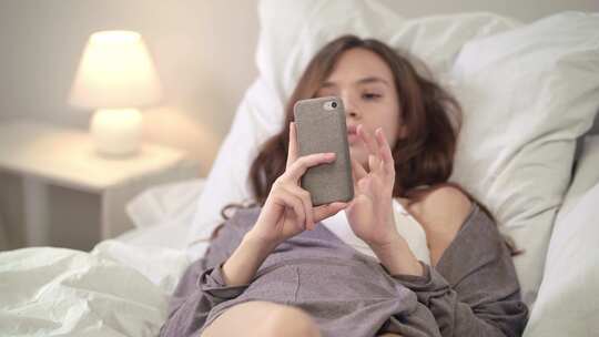 美女躺在床上看手机放松休闲视频素材模板下载
