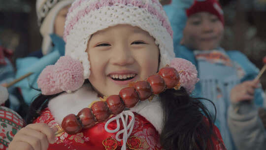 拿着糖葫芦面对着镜头微笑的女孩