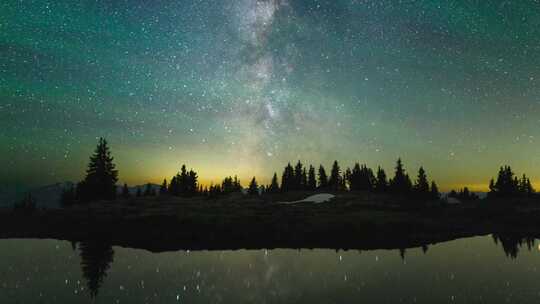 繁星璀璨的夜空下的静谧树林和湖水