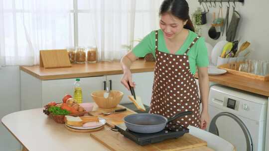 亚洲年轻女子早上在家厨房烹饪健康食品。