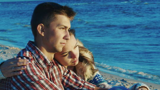 夫妇相拥坐在海滩上