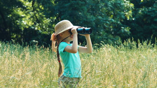 女孩站在高高的草地上透过望远镜四处观看