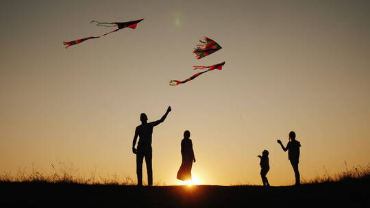 一家人在日落时分的沙滩上放风筝