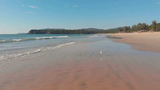 印度果阿邦阿贡达海滩海浪上空的低空无人机