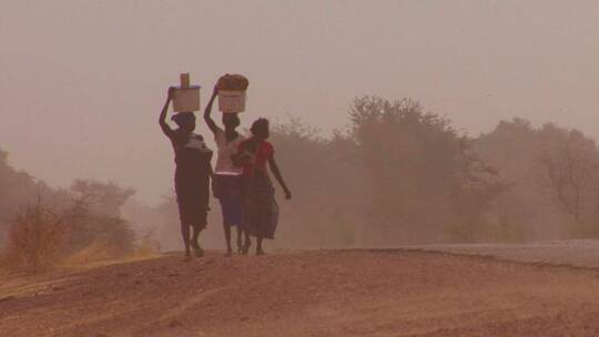 非洲妇女拿着货物在撒哈拉沙漠行走