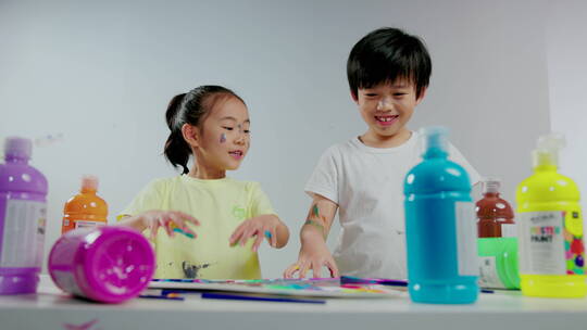 小男孩和小女孩用涂满颜料的手画画