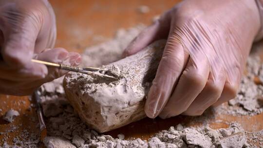 考古人员用洛阳铲铲除文物上的灰土