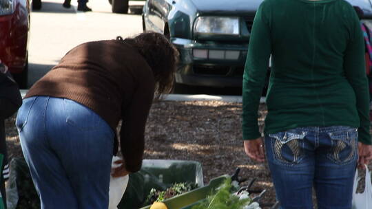 女人在路边摊挑选新鲜蔬菜