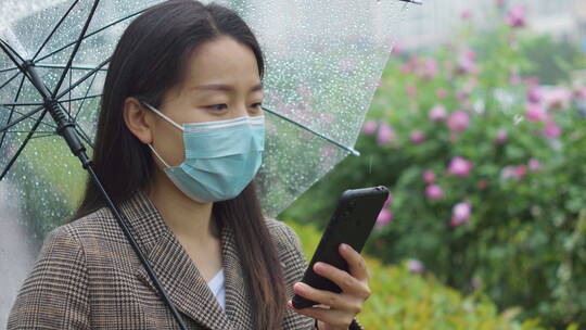 中国女性打伞步行踏春打电话等公交玩手机视频素材模板下载