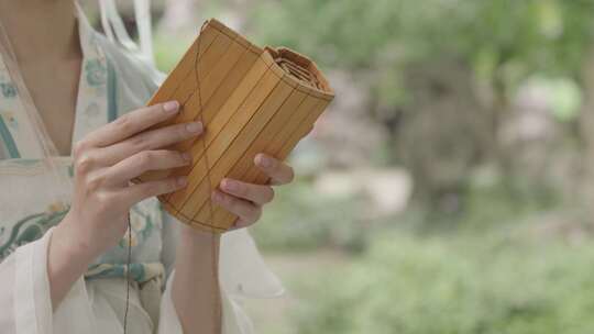 古代古风汉服女子在园林里手翻开卷轴视频素材模板下载