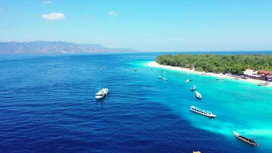 停泊在蓝色蓝色泻湖上的旅游船，靠近位于热带岛屿海岸的度假胜地，白色