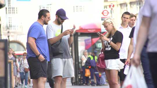 英国伦敦街道 街头行人站着使用手机的场景