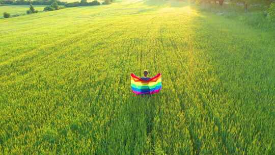 女同性恋男同性恋女孩在户外举着彩虹旗。空