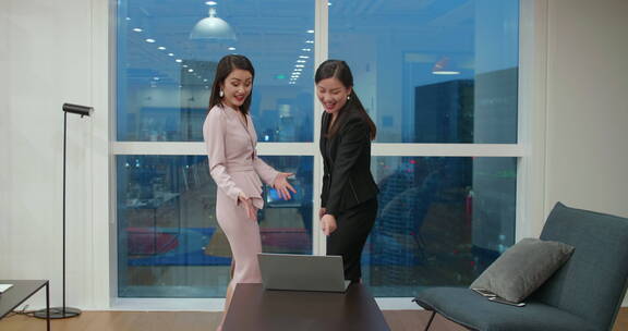 两位疯狂职业女性在办公室跳舞庆祝成功喜悦