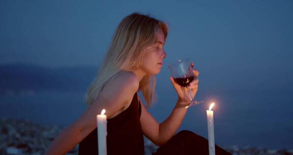 女人坐在蜡烛旁喝红酒